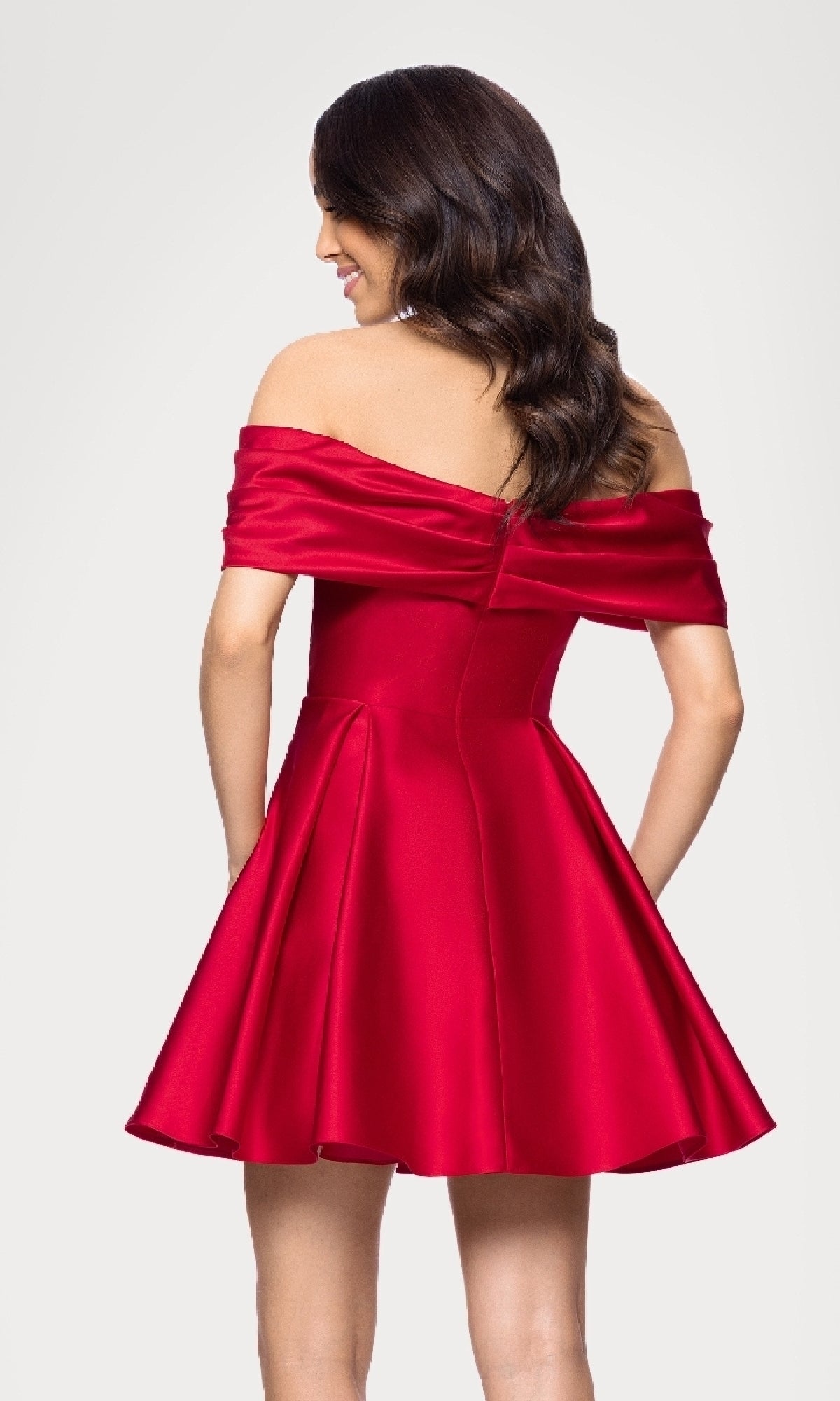 A woman stands with her back to the camera in the Blondie Nites 5695BN Off-Shoulder Red Hoco Dress, featuring a flared skirt and corset-style bodice, set against a plain background.